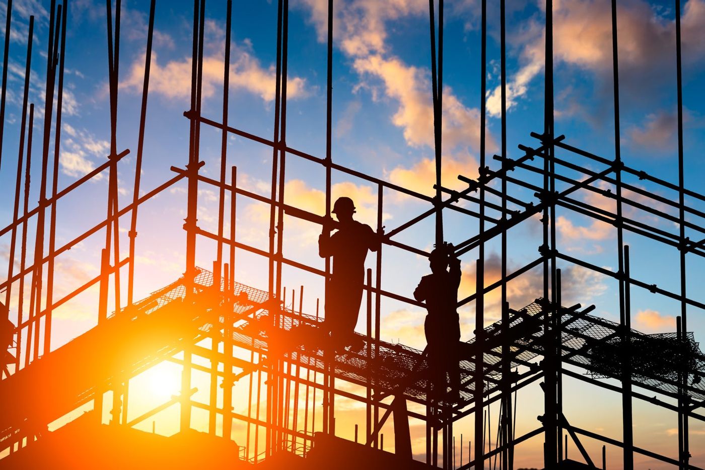 Construction workers on scaffolding at sunset